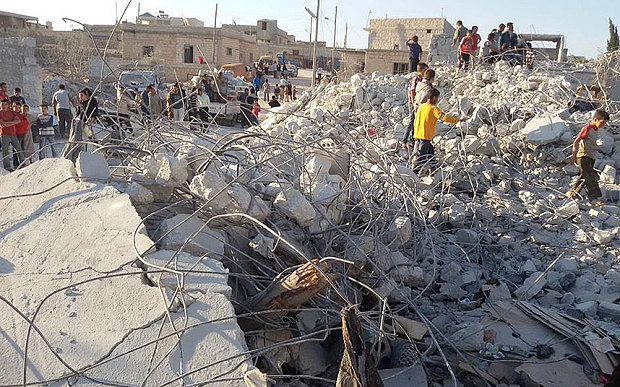 Sírios nos escombros de uma casa atacada por aliados dos EUA