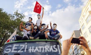 Anti-government protesters pose for a souvenir photo on top of a damaged public bus at Taksim square in Istanbul