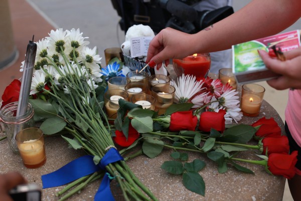 A woman lights a candle at a makeshift memorial outside of the Dallas Police Department headquarters in Dallas July 8. The prior evening gunmen shot and killed five police officers and wounded seven during a peaceful protest in downtown Dallas. The protest was in reaction after two black men were fatally shot by police officers in Baton Rouge, La., and Minneapolis. (CNS photo/Rebecca Kirstin Patton, The Texas Catholic) See DALLAS-POLICE-DEATHS July 8, 2016.