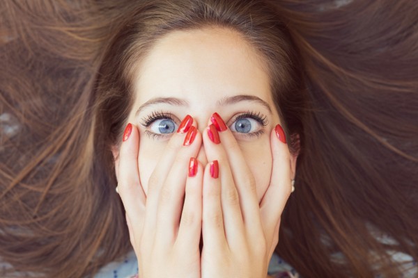 Beautiful woman with hands on face and red nails