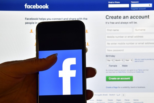 LONDON, ENGLAND - AUGUST 03: A person holds an iPhone displaying the Facebook app logo in front of a computer screen showing the facebook login page on August 3, 2016 in London, England.  (Photo by Carl Court/Getty Images)