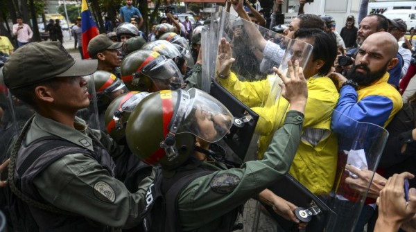 Venezuelan's opposition deputies Carlos Paparoni (C) and Carlos Bozo (R) scuffle with National Guard personnel in riot gear during a protest in front of the Supreme Court in Caracas on March 30, 2017. Venezuela's Supreme Court took over legislative powers Thursday from the opposition-majority National Assembly, whose speaker accused leftist President Nicolas Maduro of staging a "coup." / AFP / JUAN BARRETO