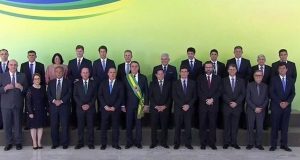 Foto da equipe ministerial de Bolsonaro no dia 01 de janeiro de 2019, com ele no meio. Todos estão sentados lado a lado.