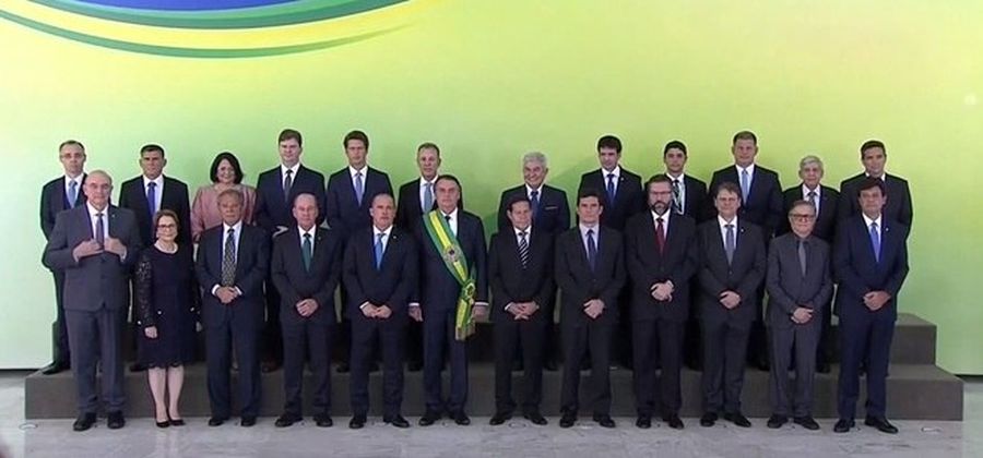 Foto da equipe ministerial de Bolsonaro no dia 01 de janeiro de 2019, com ele no meio. Todos estão sentados lado a lado.