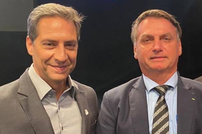 Lacombe ao lado de Bolsonaro, ambos sorrindo para a foto