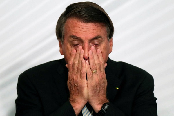 Jair Bolsonaro com as mãos no rosto