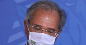 Paulo Guedes de máscara com a cabeça baixa