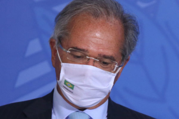 Paulo Guedes de máscara com a cabeça baixa