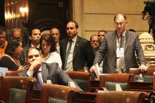 Carlos Bolsonaro cercado de dois guarda-costas no plenário da Câmara de Vereadores do Rio de Janeiro