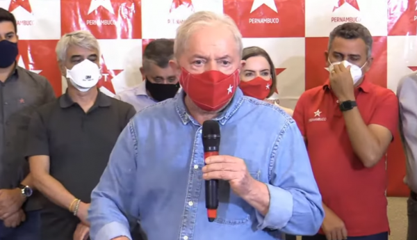Lula segurando o microfone e usando máscara