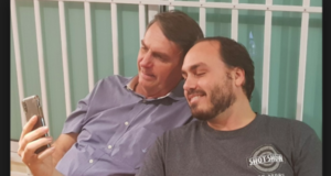 Bolsonaro e o filho, Carlos, olhando para um celular