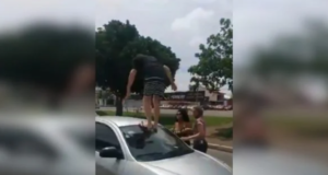 Homem sobe em cima de carro