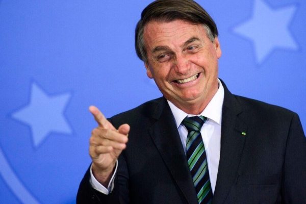 Bolsonaro rindo, com o dedo indicador erguido