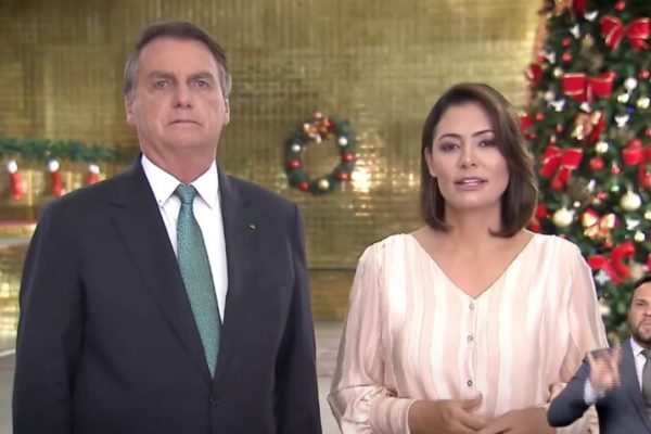 Bolsonaro e Michelle, de pé, com enfeites de Natal ao fundo