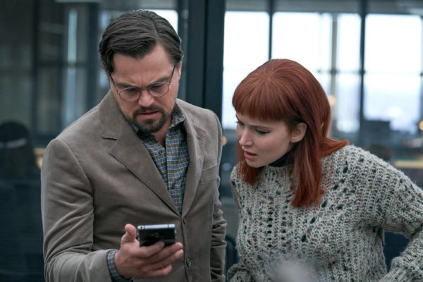 Leonardo Di Caprio olhando para um celular com colega de elenco do filme Não Olhe para Cima, da Netflix