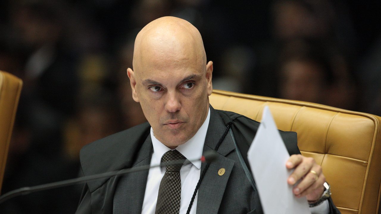 Foto de Alexandre de Moraes com olhar sério. Ele é calvo e está em uma cadeira no plenário do STF