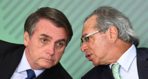 Paulo Guedes falando no ouvido de Bolsonaro.