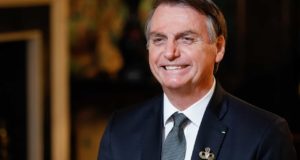 Bolsonaro, que é aliado do Centrão, sentado e sorrindo