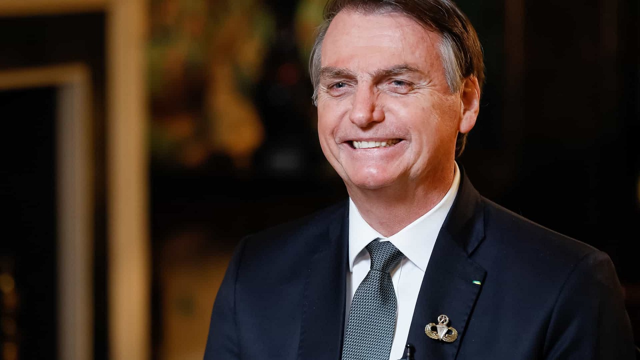 Bolsonaro, que é aliado do Centrão, sentado e sorrindo