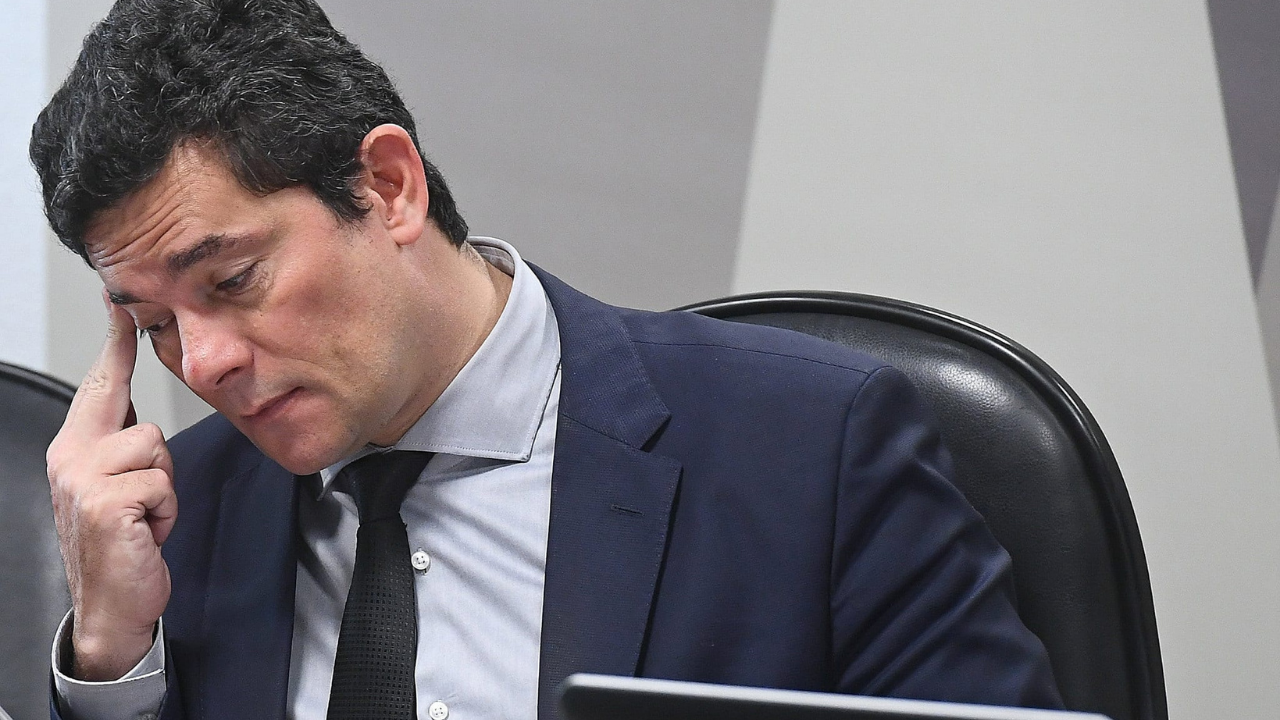 foto de Sergio Moro com olhar preocupado. Cabeça abaixada, franzindo a testa com a mão direita na cabeça.