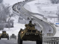 Foto de tanque de guerra em uma estrada. Está nevando, há uma fila de tanques ao fundo