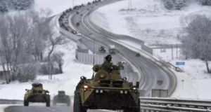 Foto de tanque de guerra em uma estrada. Está nevando, há uma fila de tanques ao fundo