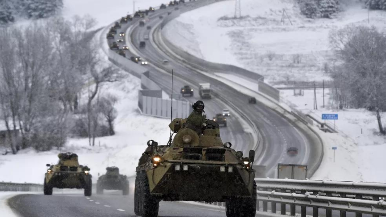 Foto de tanque de guerra em uma estrada. Está nevando, há uma fila de tanques ao fundo