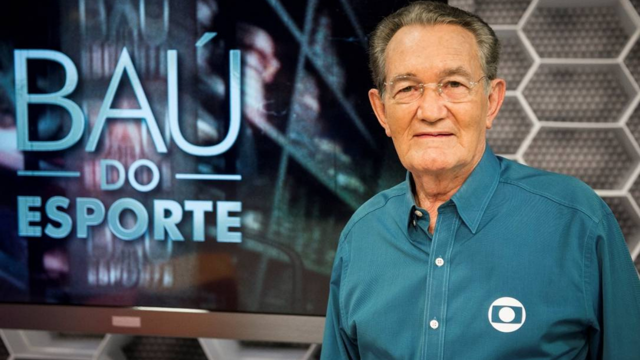 Foto de Léo Batista com cabelos grisalhos, usando óculos e camisa ao azul. No lado esquerda imagem tem "Baú do Esporte", quadro do programa Globo Esporte que ele apresentava