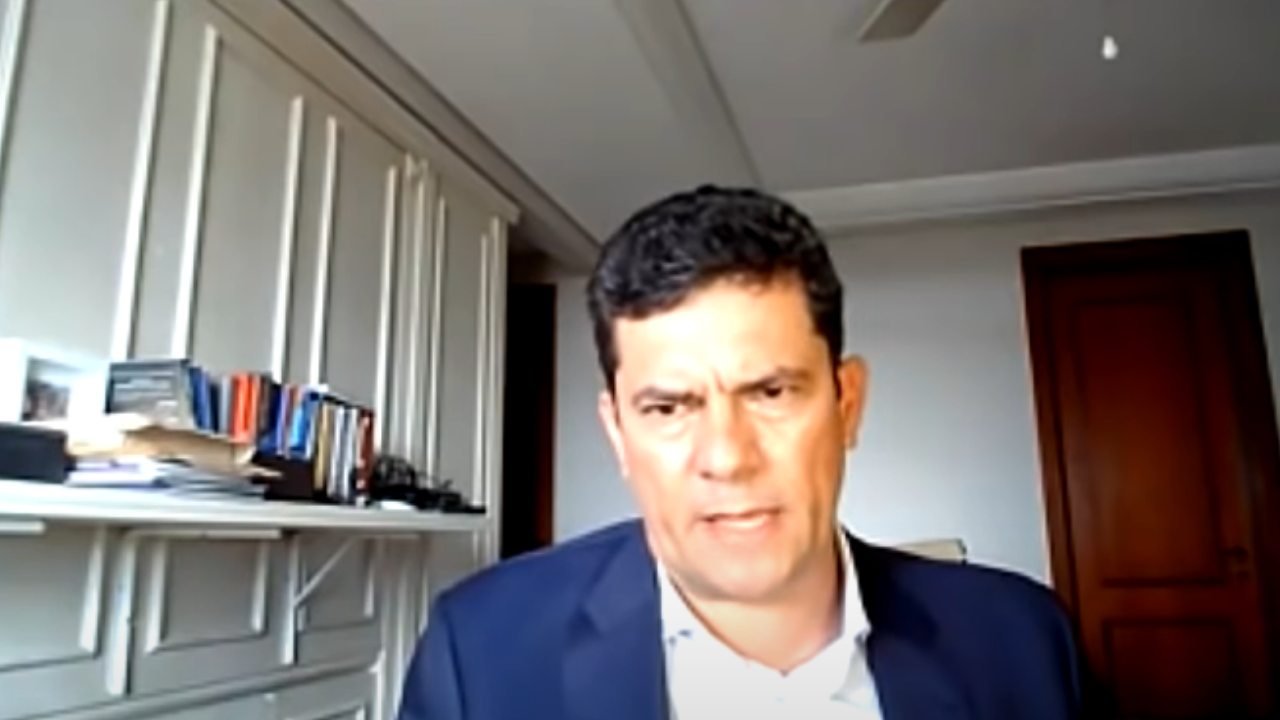 Foto de Sérgio Moro usando terno preto. É um print de uma entrevista no YouTube, ele está sério.