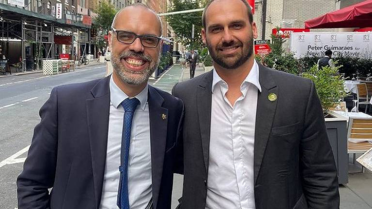 Foto de Allan dos Santos e Eduardo Bolsonaro juntos. Eles usam terno.