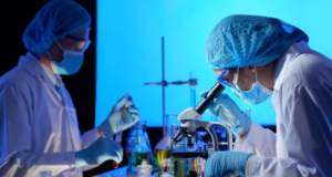 foto de cientistas em laboratório. Há microscópios e eles usam roupas de proteção.