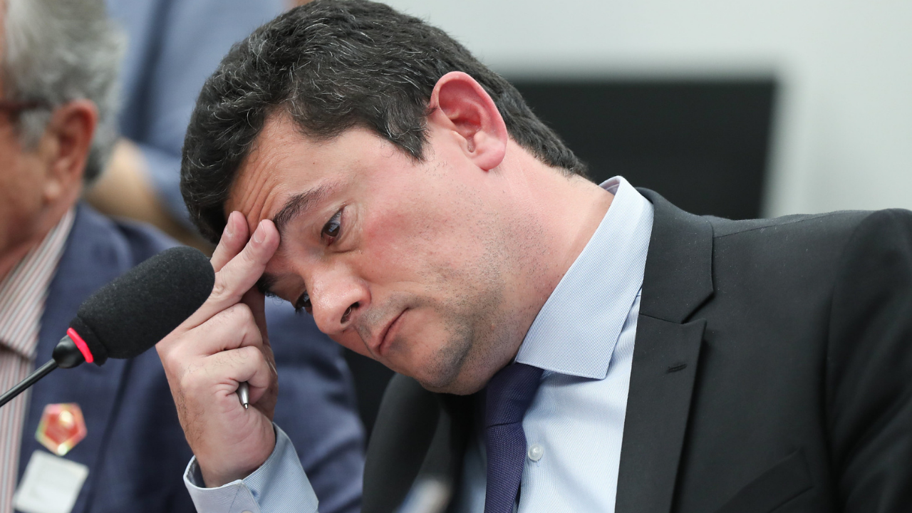 Foto de Sergio Moro preoupado com a cabeça deixada pra lateral apoiada na mão direita