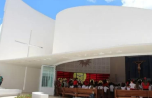 Escola em Itaúna com fachada branca, símbolos católicos, como cruzes