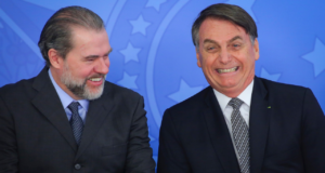 Foto de Dias Toffoli e Bolsonaro sorrindo. Toffoli tem barba com pelos grisalhos e cabelo preto liso.