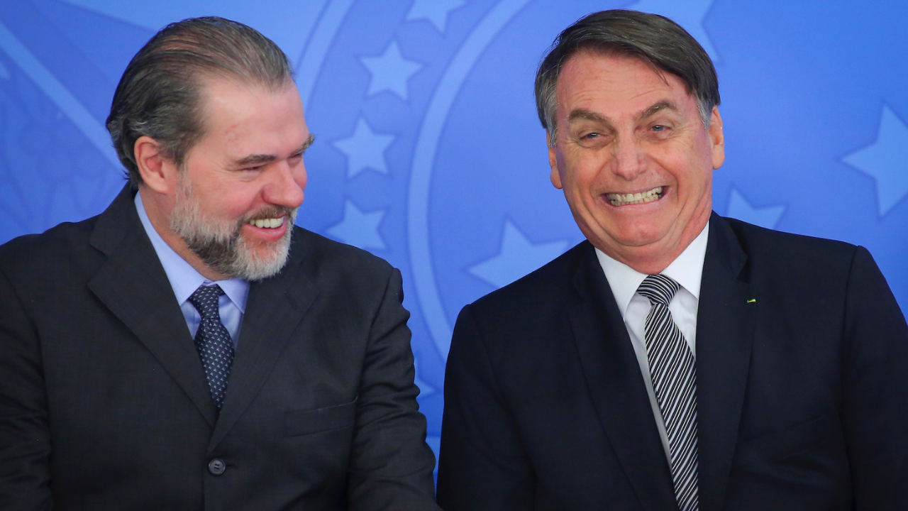 Foto de Dias Toffoli e Bolsonaro sorrindo. Toffoli tem barba com pelos grisalhos e cabelo preto liso.