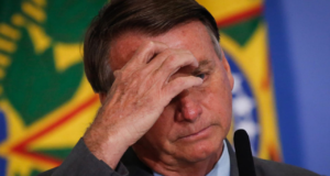 Foto de Bolsonaro com mão cobrindo o rosto. Aparenta estar preocupado.