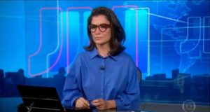 Renata Vasconcellos sentada na bancada do Jornal Nacional