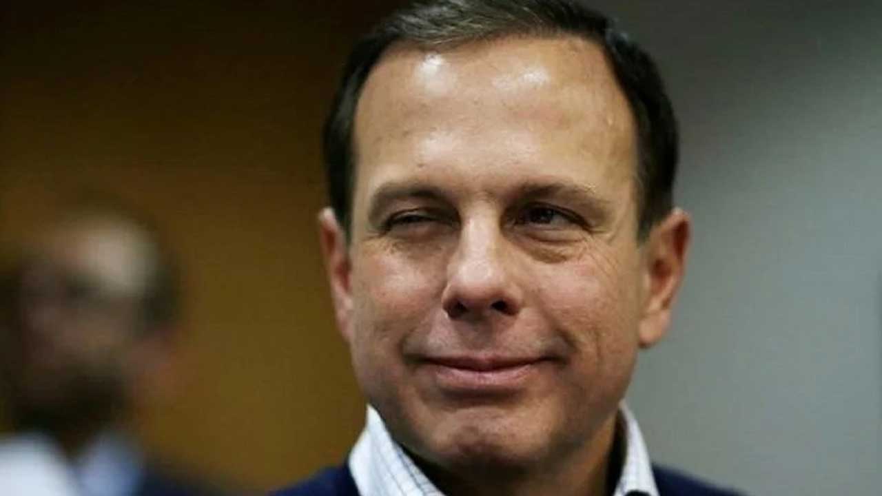 João Doria olhando meio de lado e com uma piscadela e leve sorriso