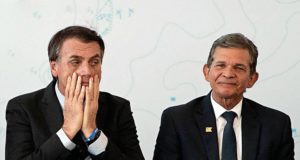 Bolsonaro com a mão no rosto e expressão de cansado ao lado de Joaquim Silva e Luna, presidente da Petrobras, que sorri de forma modesta.