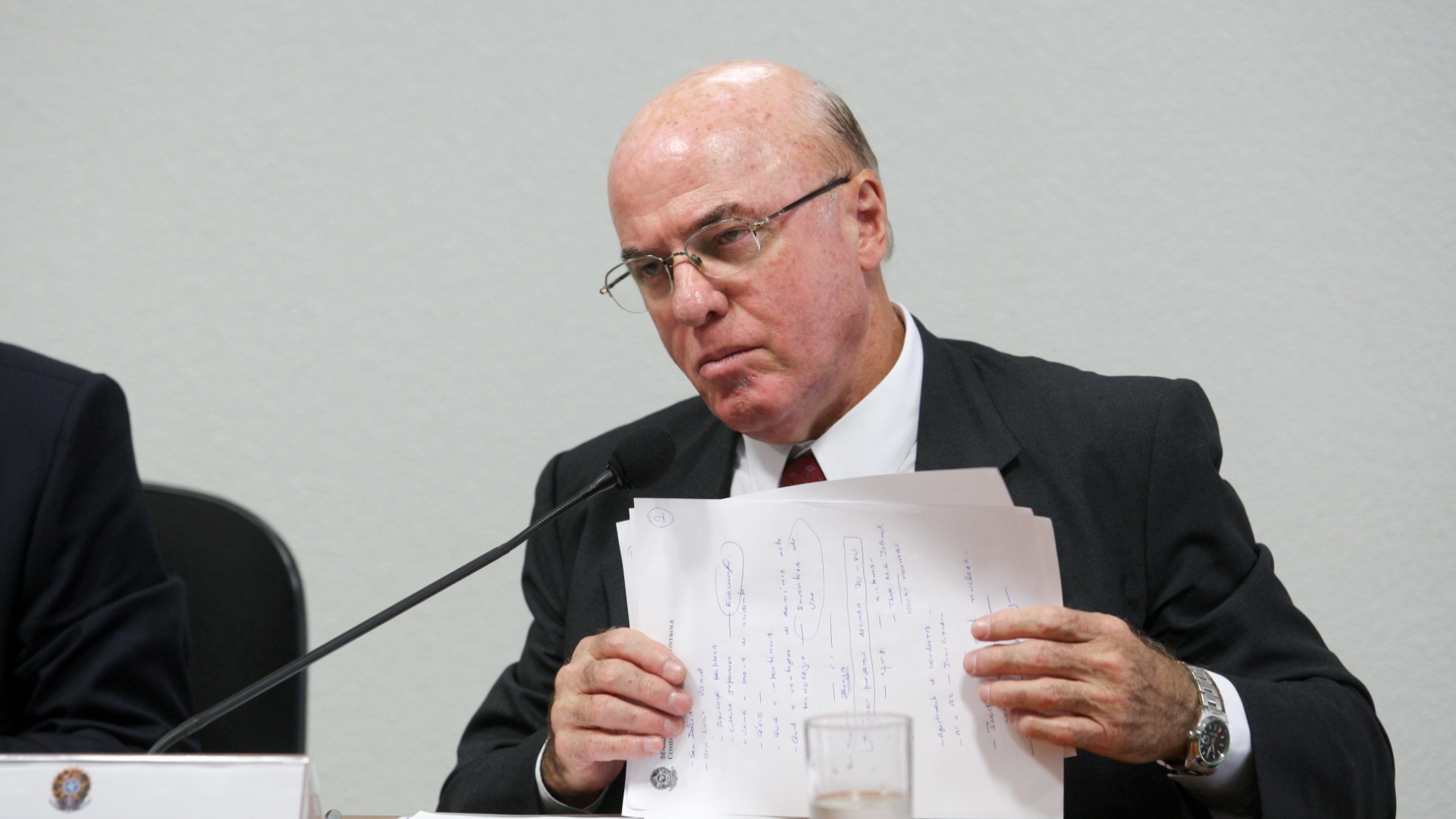 Amirante Othon com papéis nas mãos, sentado, durante discurso