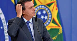 Ex-ministro de Bolsonaro abandona cargo no TSE. O presidente olha para o lado direito com a mão na cabeça e aaparência de estar preocupado.