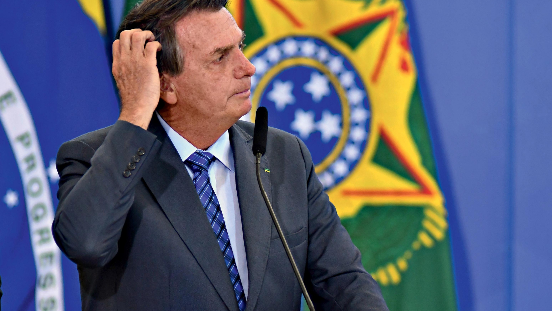 Ex-ministro de Bolsonaro abandona cargo no TSE. O presidente olha para o lado direito com a mão na cabeça e aaparência de estar preocupado. 