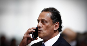 Wassef, advogado de Bolsonaro, vira réu por racismo. Ele tem pele parda, fala ao microfone, usa terno preto e gravata azul.