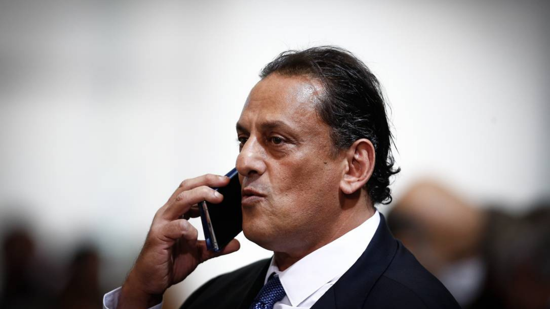 Wassef, advogado de Bolsonaro, vira réu por racismo. Ele tem pele parda, fala ao microfone, usa terno preto e gravata azul.