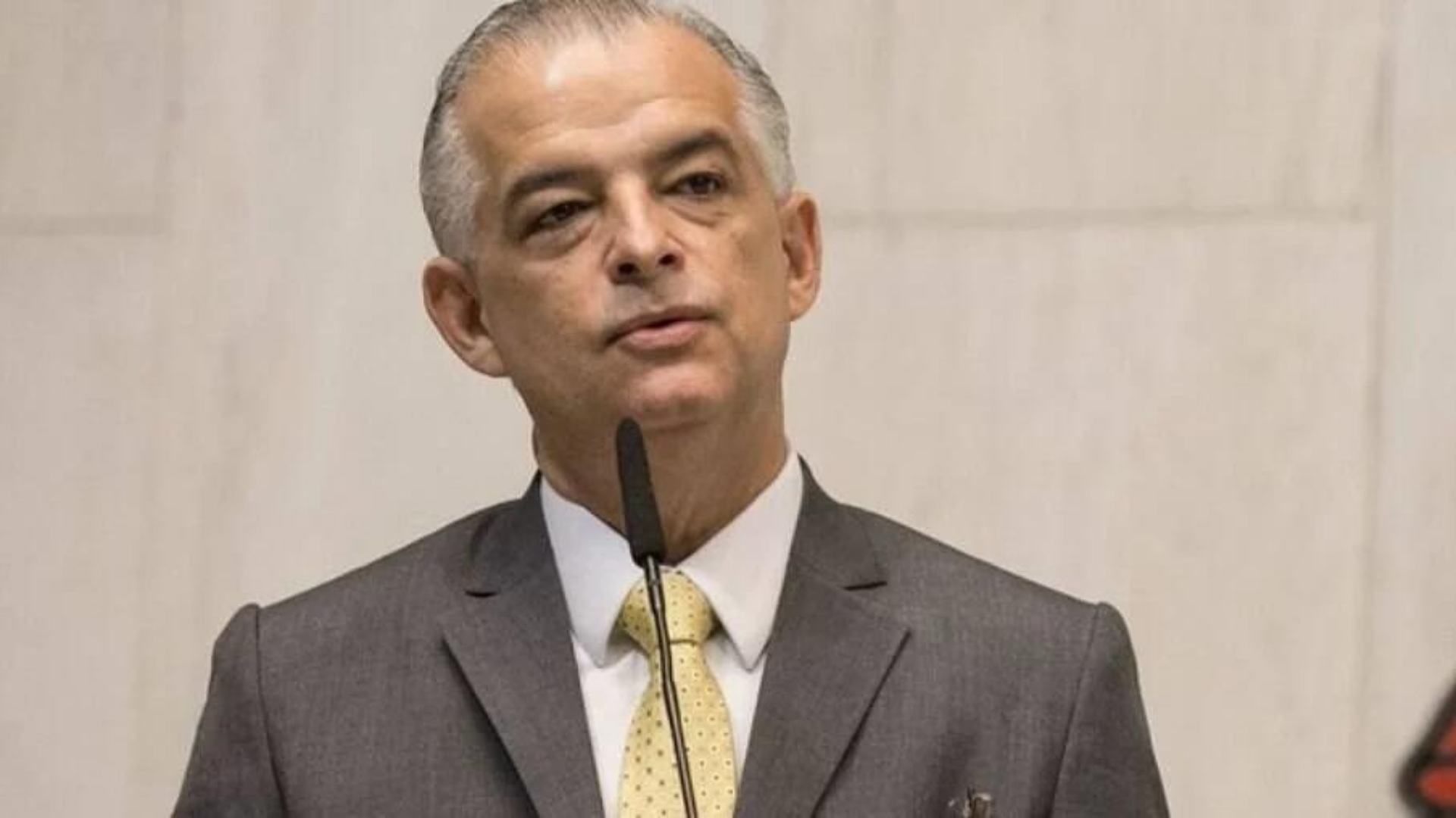 Márcio França bate o pé e vira pedra no sapato do PSB em São Paulo. Ele, que tem cabelo grisalho, fala ao microfone com um terno cinza.