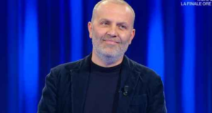 O médico que liderou movimento antivacina, Pasquale Bacco está em um estúdio de TV, com roupas pretas e olhar sério. Ele usa barba branca e cabelo calvo.