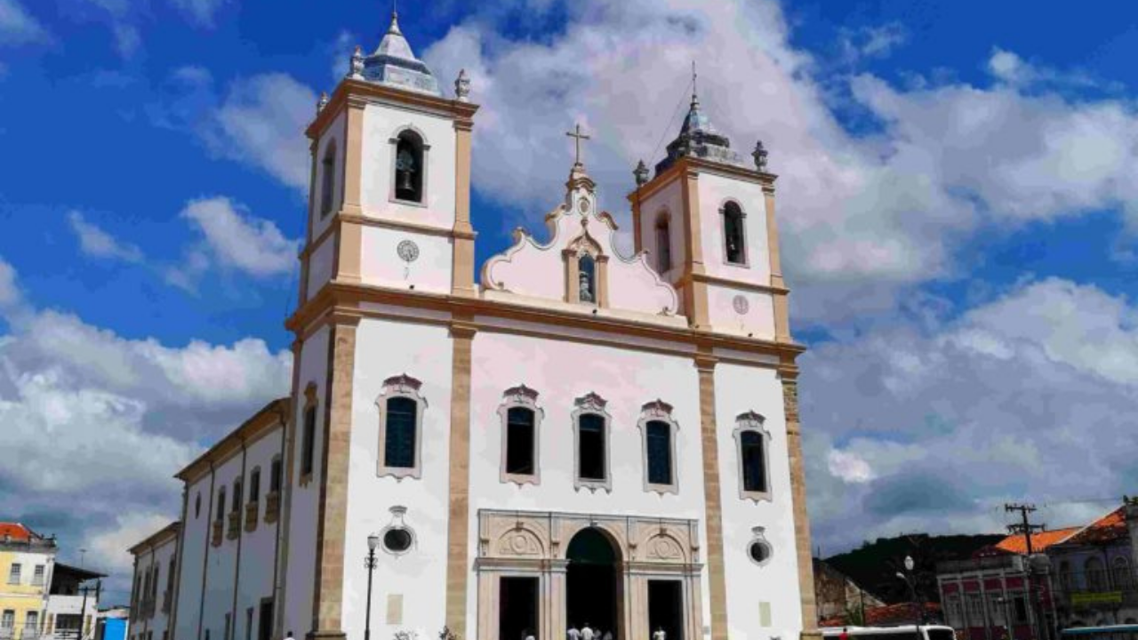 Foto da igreja  deSanto Amato da Purificação. Ela é branca com cores em dourado e janeças azuis. tem suas torres.