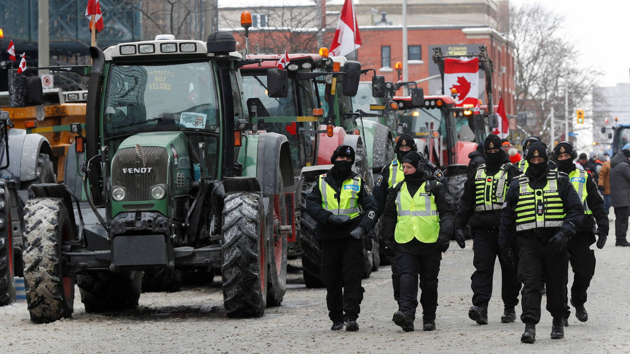 Prefeito de Ottawa decreta estado de emergência. Policiais caminham na neve enquanto caminhões bloqueiam rua.