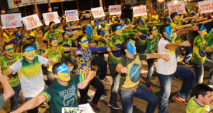 Responsável pela Dança Fora Dilma confessa ter se arrependendido. Na foto, pessoas pintadas de verde e amarelo fazem dança na rua com cartazes escritos "Fora Lula".