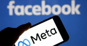 Foto de celular com a logo da Meta, ao fundo há o nome 'Facebook" em branco com painel azul